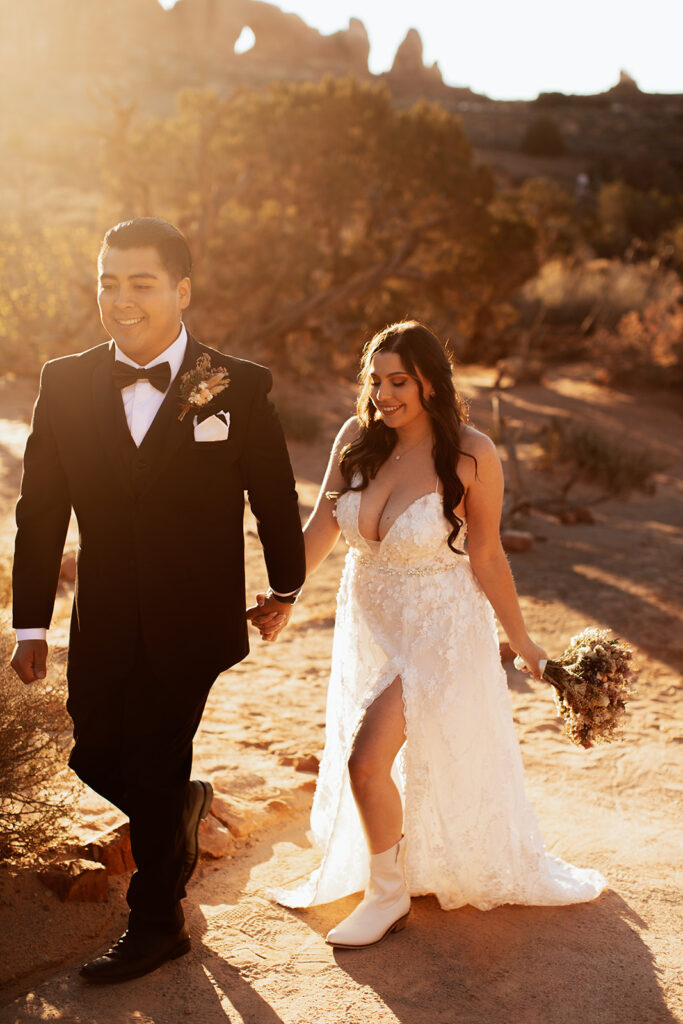 couple walks holding hands at red rock elopement