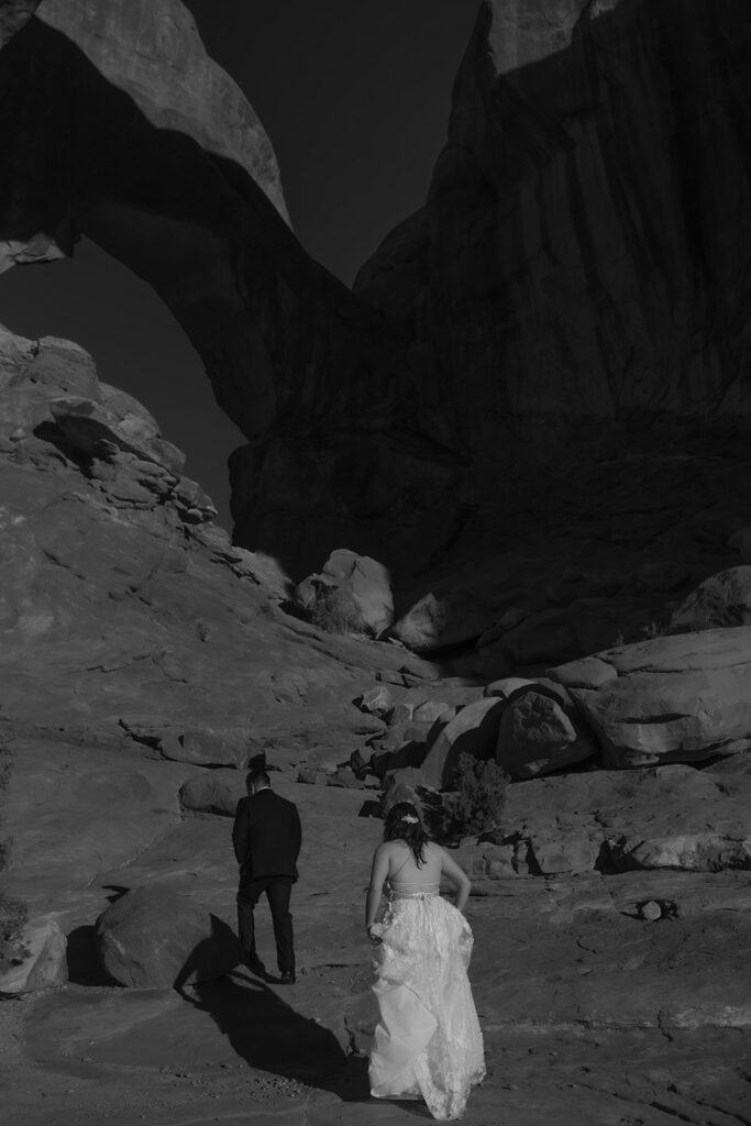 couple walks along arches at Arches National Park Moab elopement
