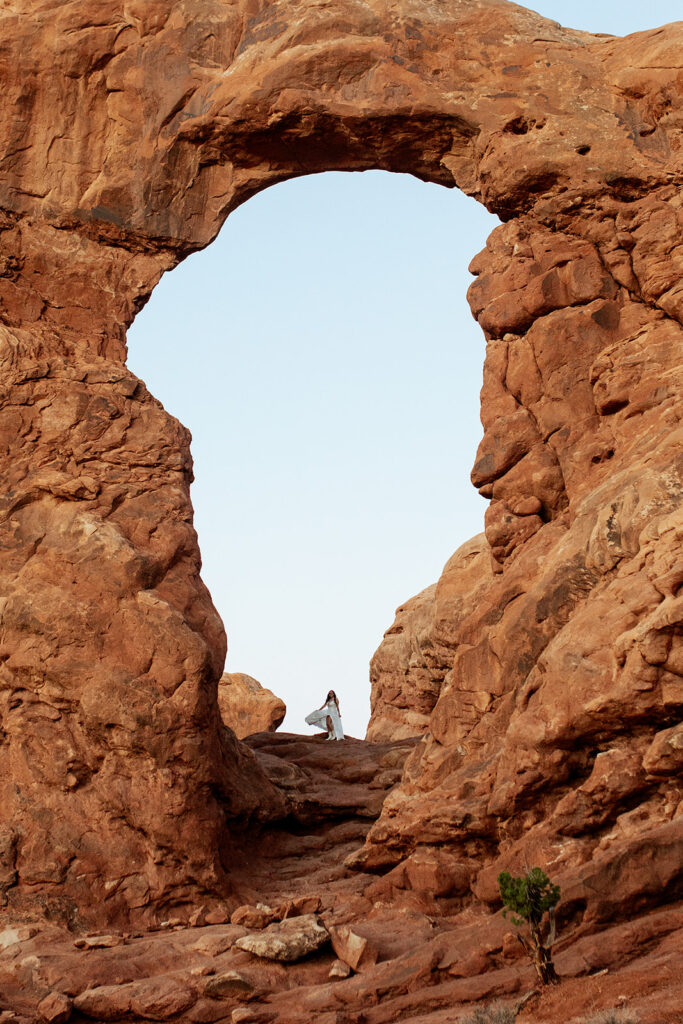 bride stands under arches at Arches National Park Moab elopement