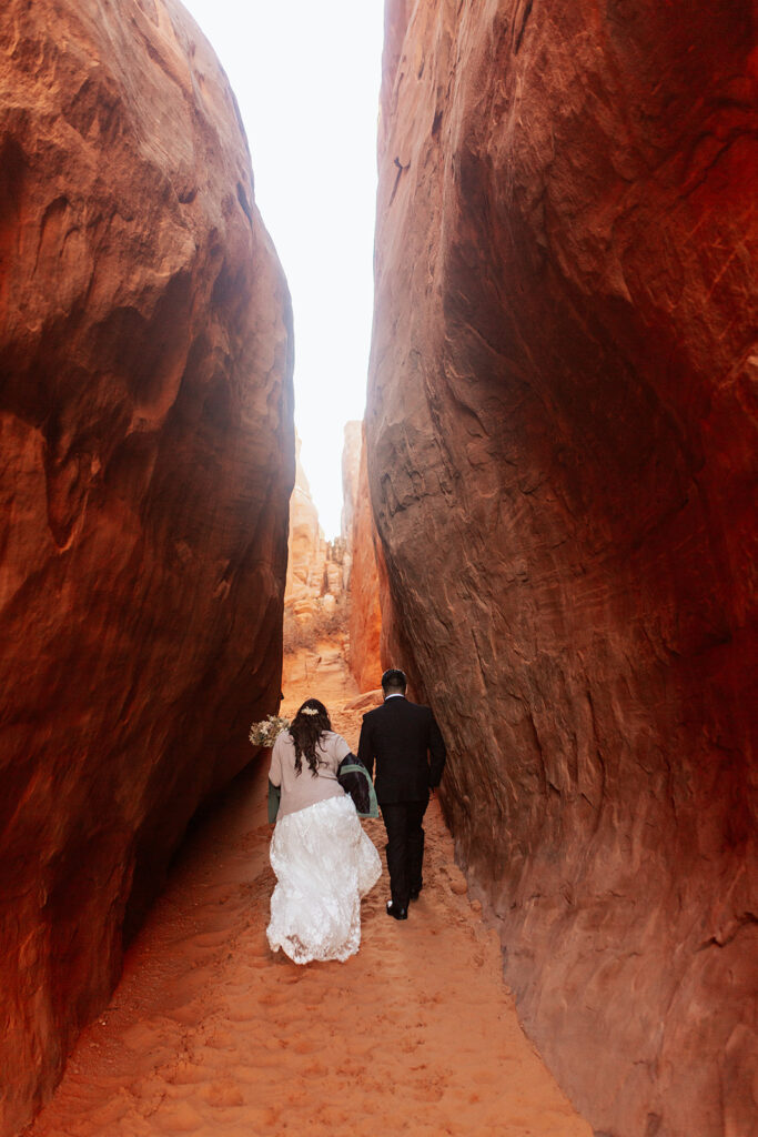 couple walks through tunnel at arches national park elopement