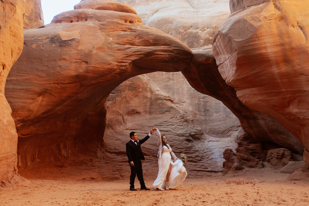 couple twirls under arches at Arches elopement