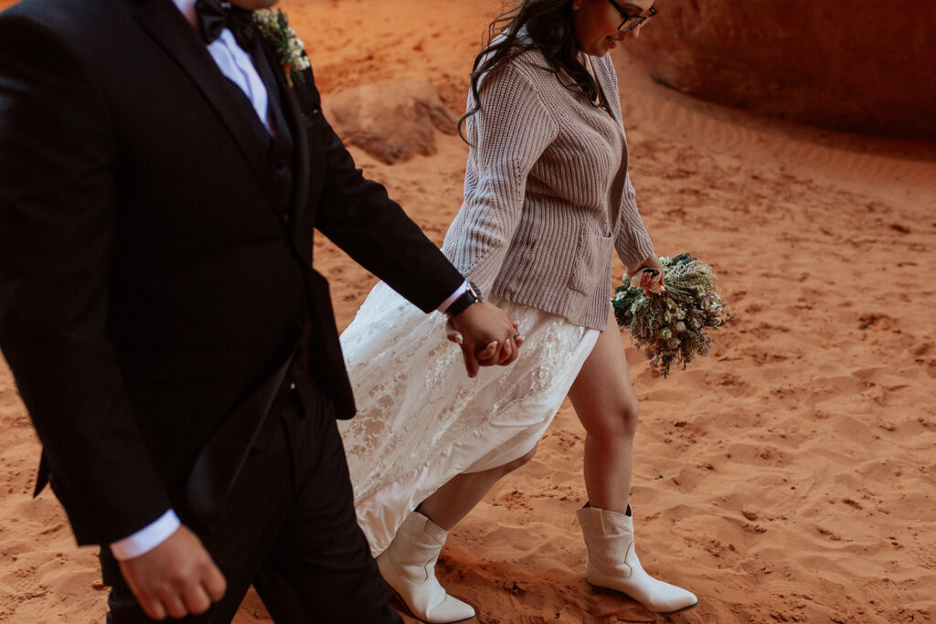 couple walks holding hands at Moab elopement
