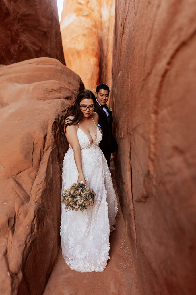 couple squeezes through cracks at Moab elopement