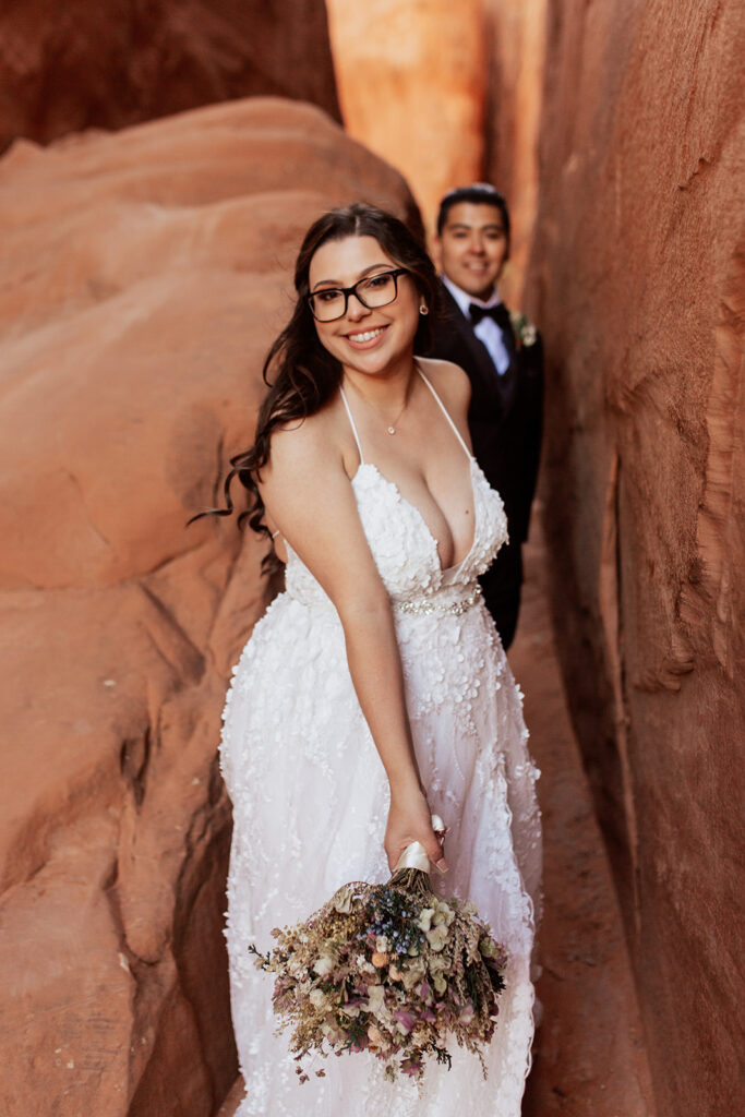 couple squeezes through cracks at Moab elopement