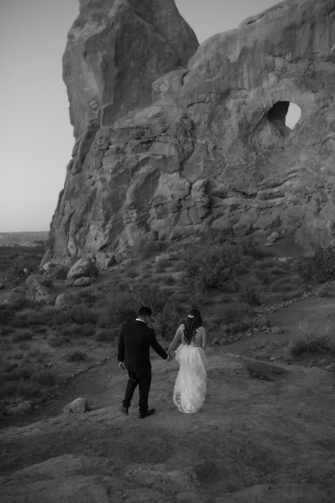 couple walks along arches at Arches National Park Moab elopement
