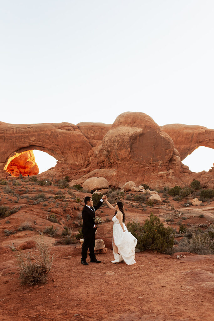 couple twirls in front of arches at Arches National Park Moab elopement