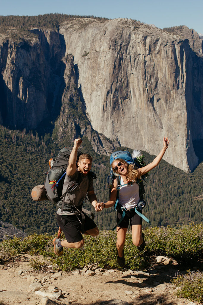 couple jumps wearing Yosemite backpacking gear