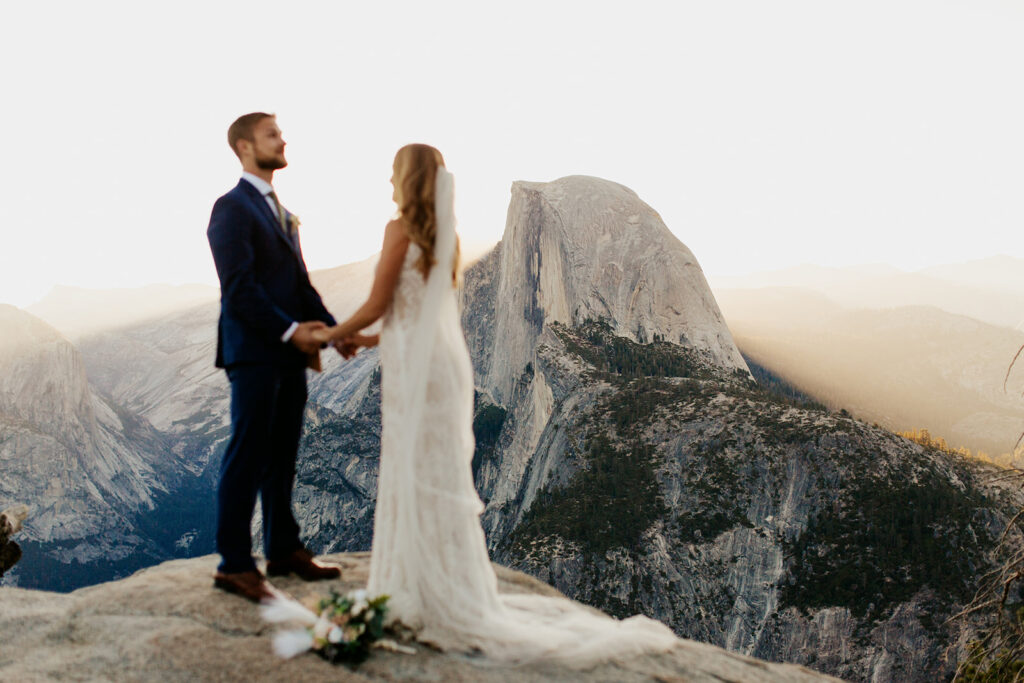 couple holds hands at Glacier Point during sunrise elopement