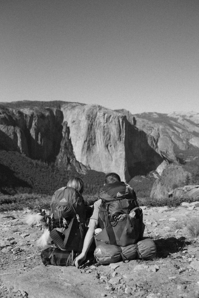 couple sits over Yosemite Valley wearing Yosemite backpacking gear
