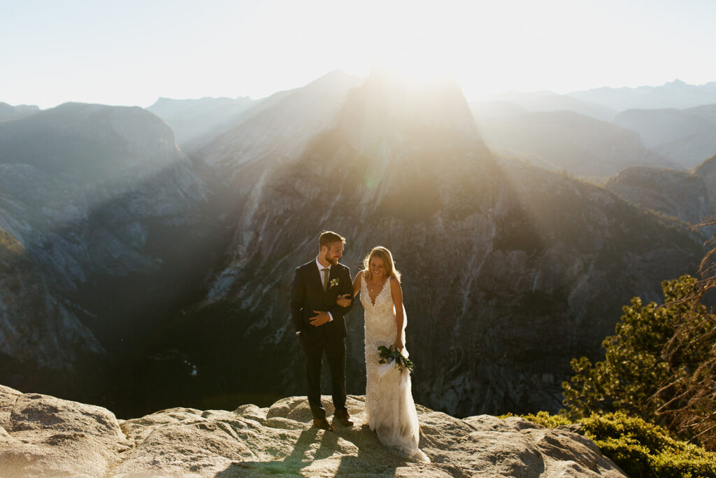 couple walks in front of Half Dome  at sunrise elopement