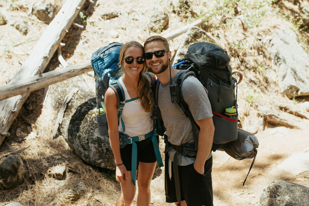 couple smiles together wearing Yosemite backpacking gear