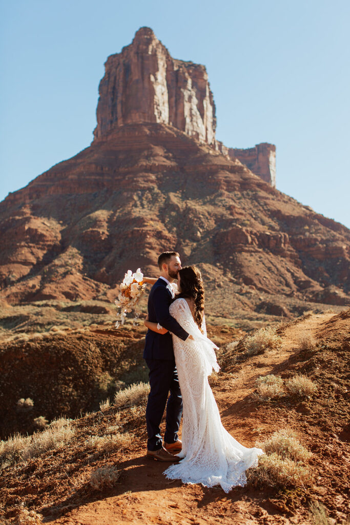 couple stands in front of monument at Castle Valley elopement