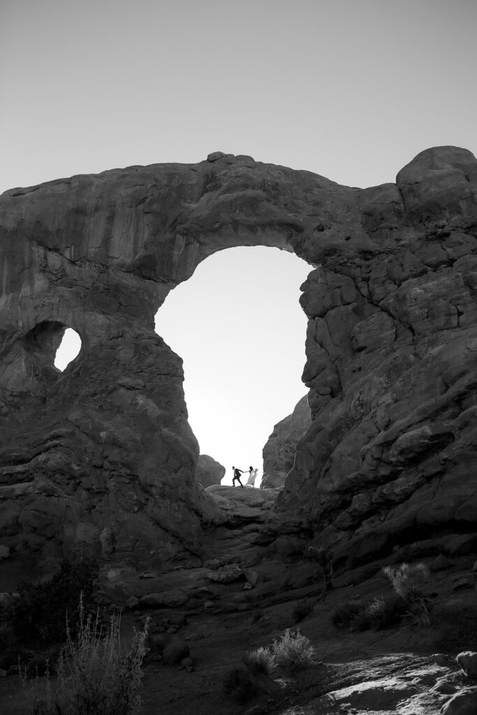 couple walks under arches at Arches National Park