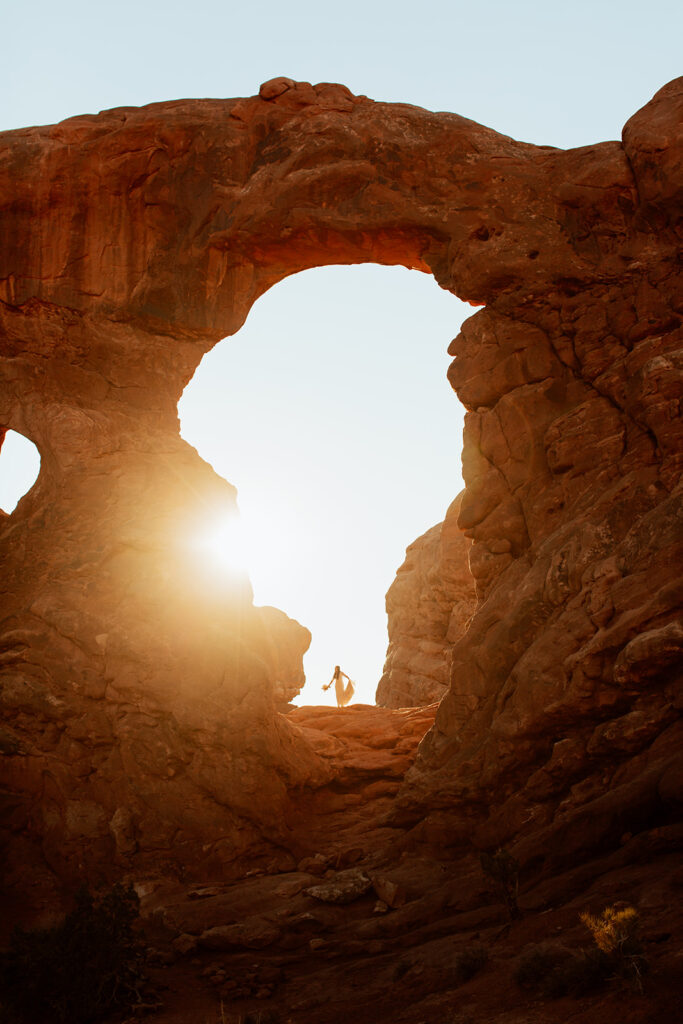 couple walks under arches at sunset Moab adventure elopement