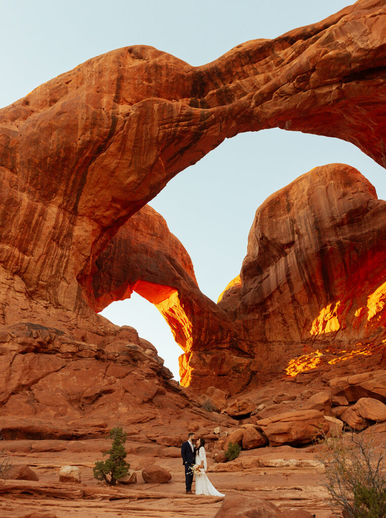 couple stands under arches at Arches National Park