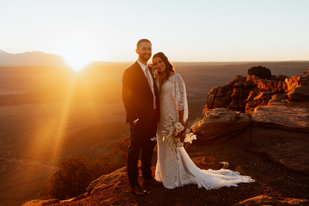 couple stands on cliff edge at Moab adventure elopement