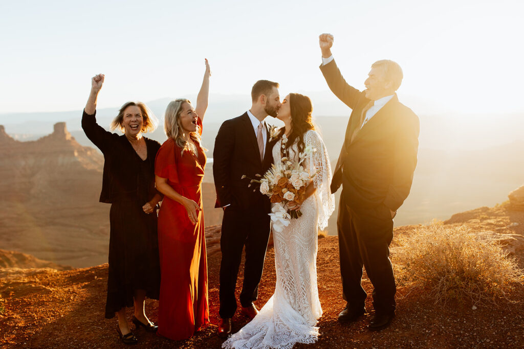 family cheers couple kissing at Moab adventure elopement