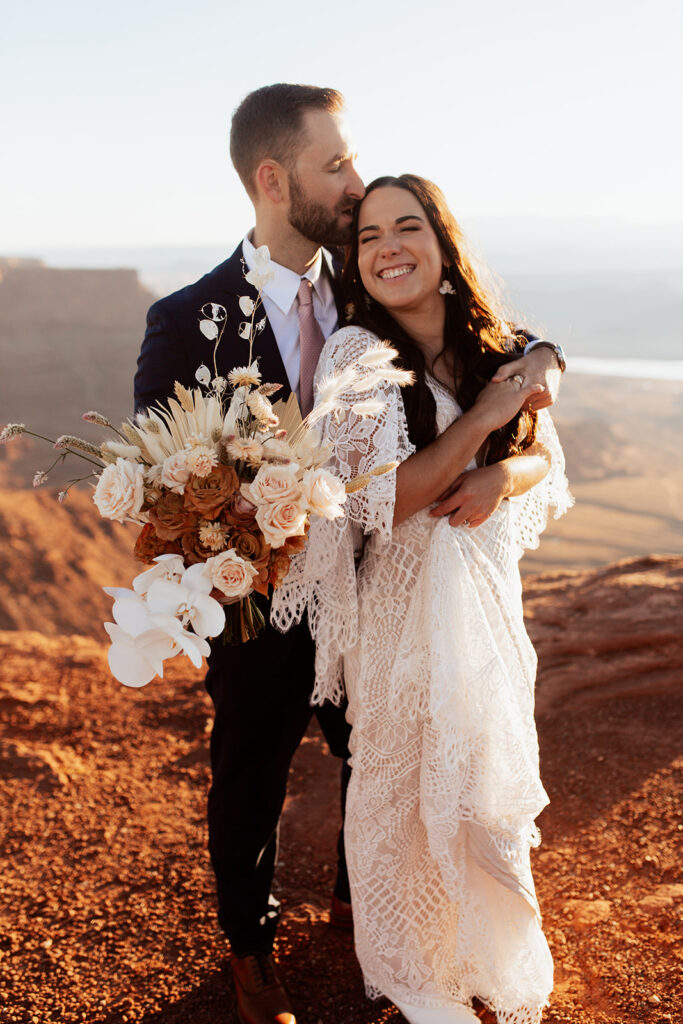 couple embraces with boho wedding bouquet at Moab adventure elopement