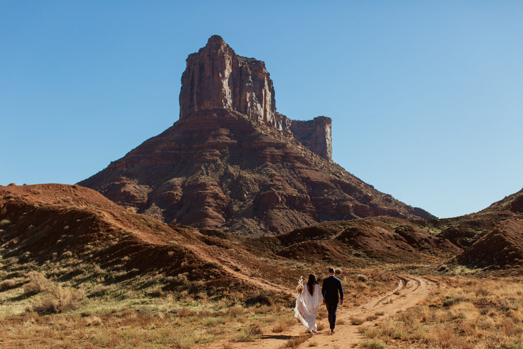 couple walks by monument at Castle Valley elopement