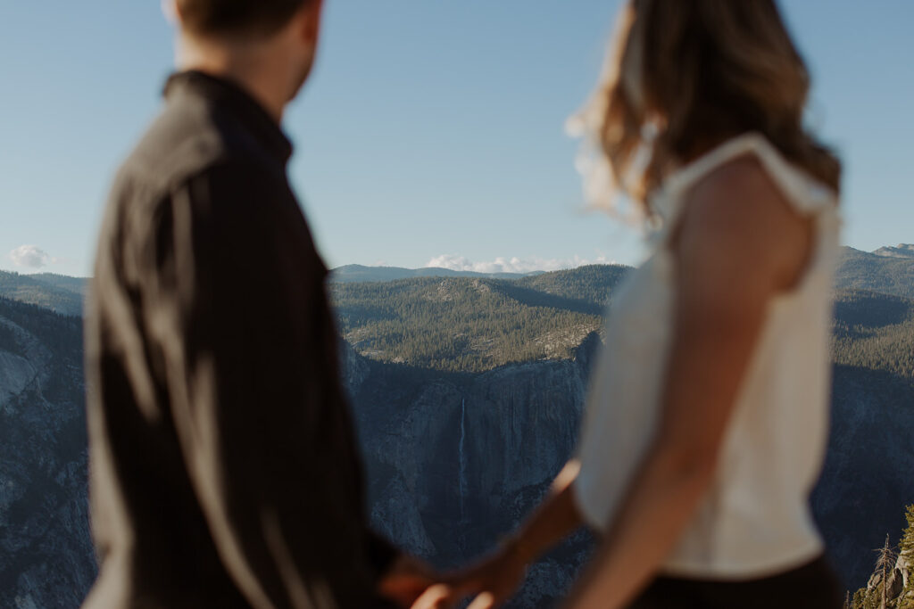 couple looks at green trees from Taft Point overlook