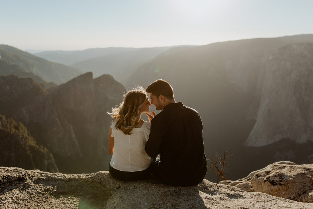 couple sits on cliff at sunset Taft Point engagement