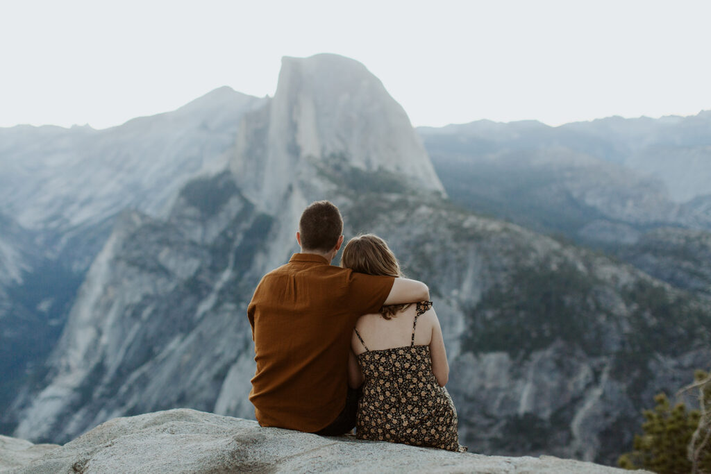 couple sits on Glacier Point overlook in Yosemite