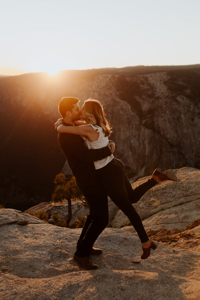couple kisses at sunset Taft Point Yosemite engagement