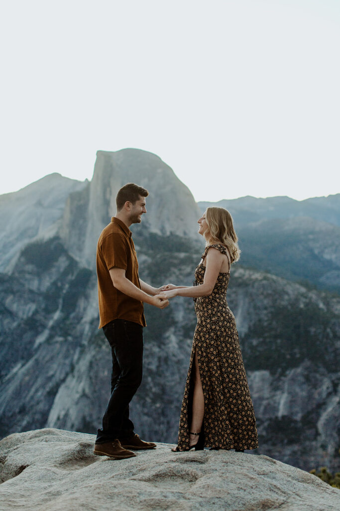 couple holds hands in front of half dome in Yosemite