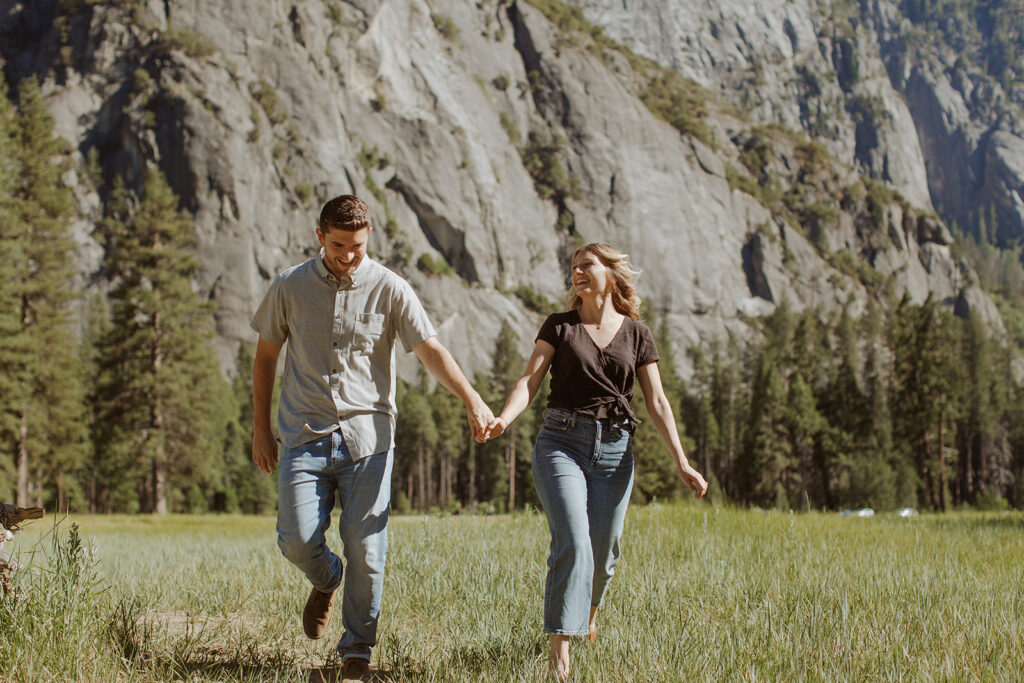 couple runs holding hands through Yosemite valley