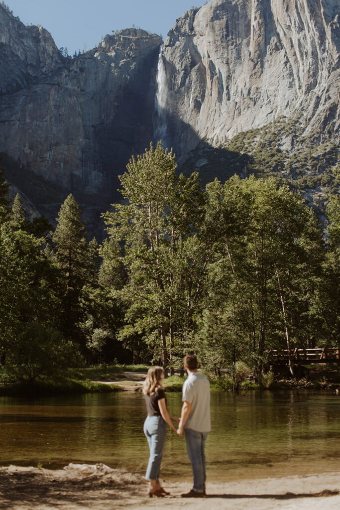 couple stands beside water at Yosemite Valley river