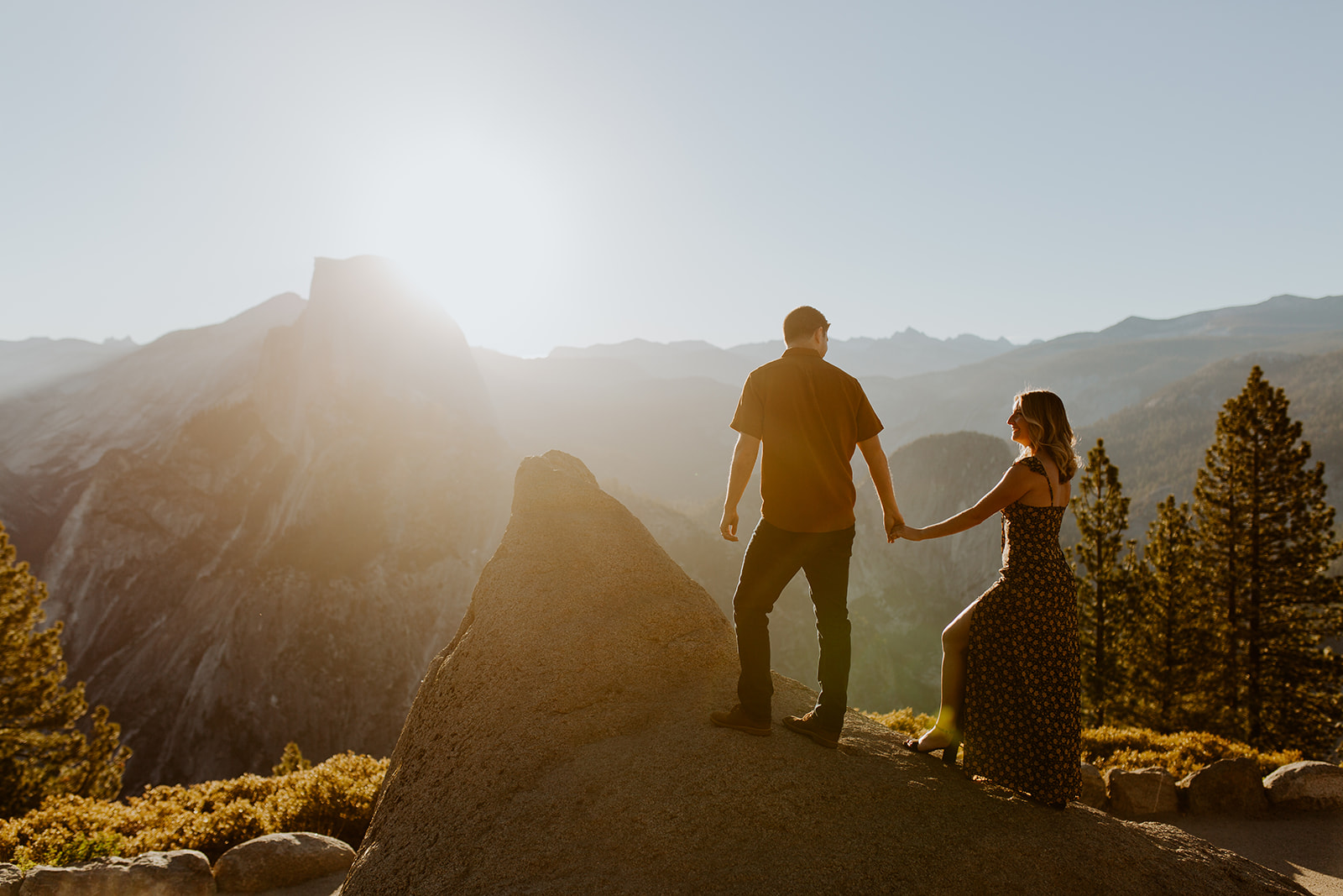 couple stand on overlook at Yosemite sunrise engagement