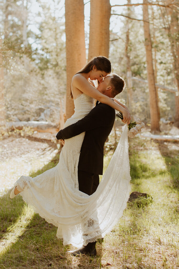groom lifts bride at sunrise forest elopement