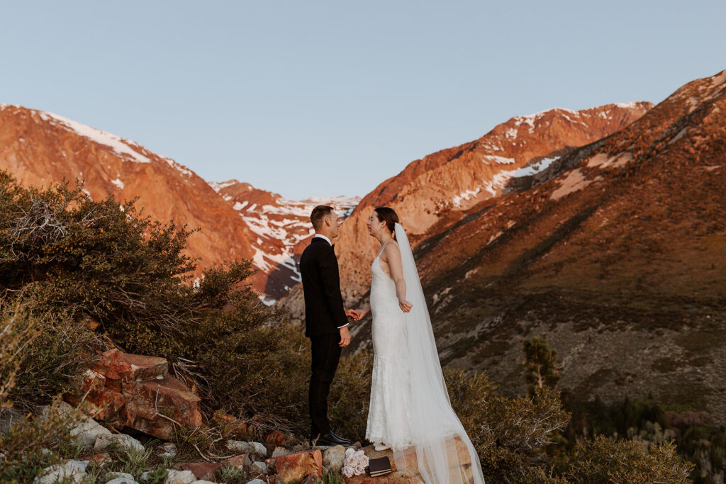 couple sings below Sierra Nevadas at snow-covered mountain elopement