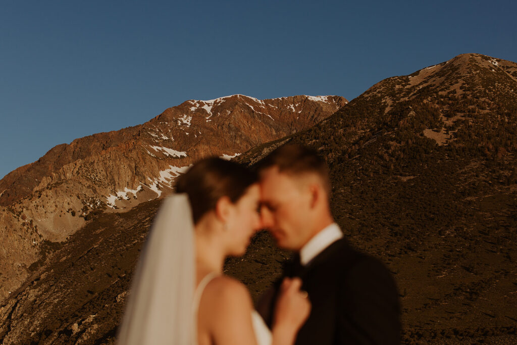 couple embraces below Sierra Nevadas snow-covered mountain tops