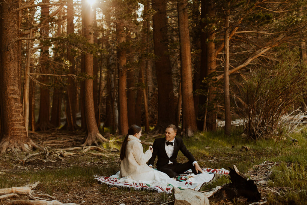 couple sits at picnic by the woods at mountain elopement