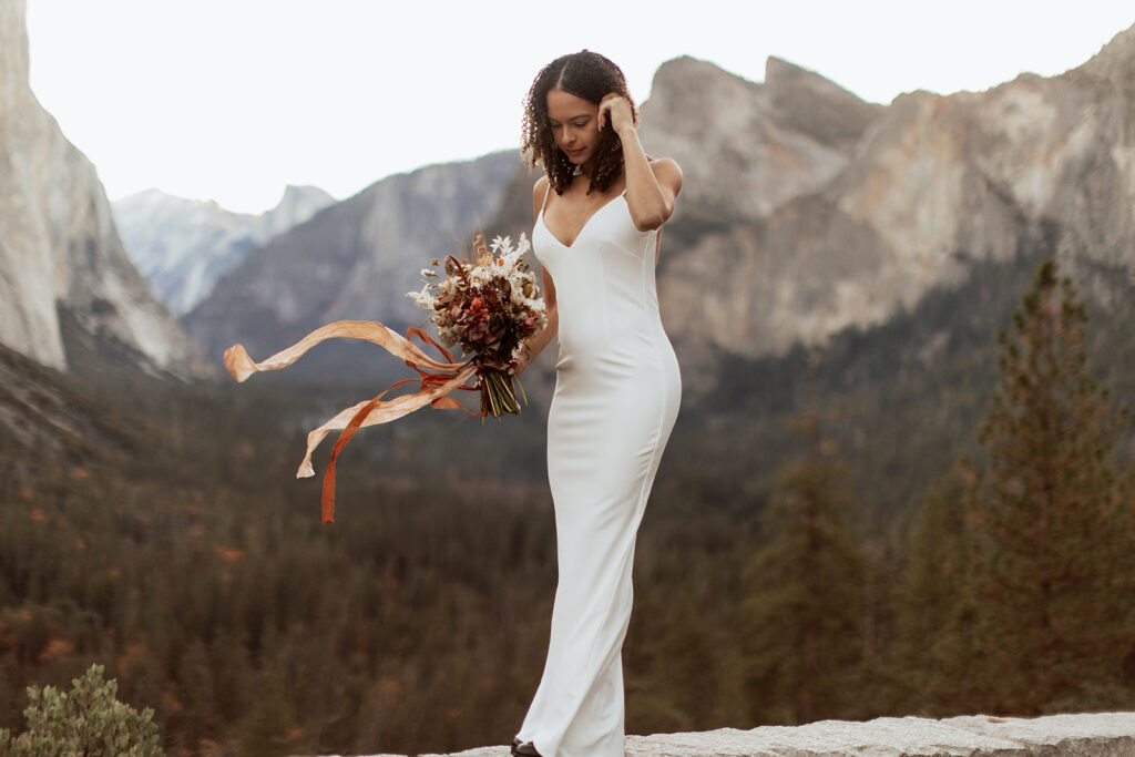 bride holds red wildflower bouquet at Yosemite elopement