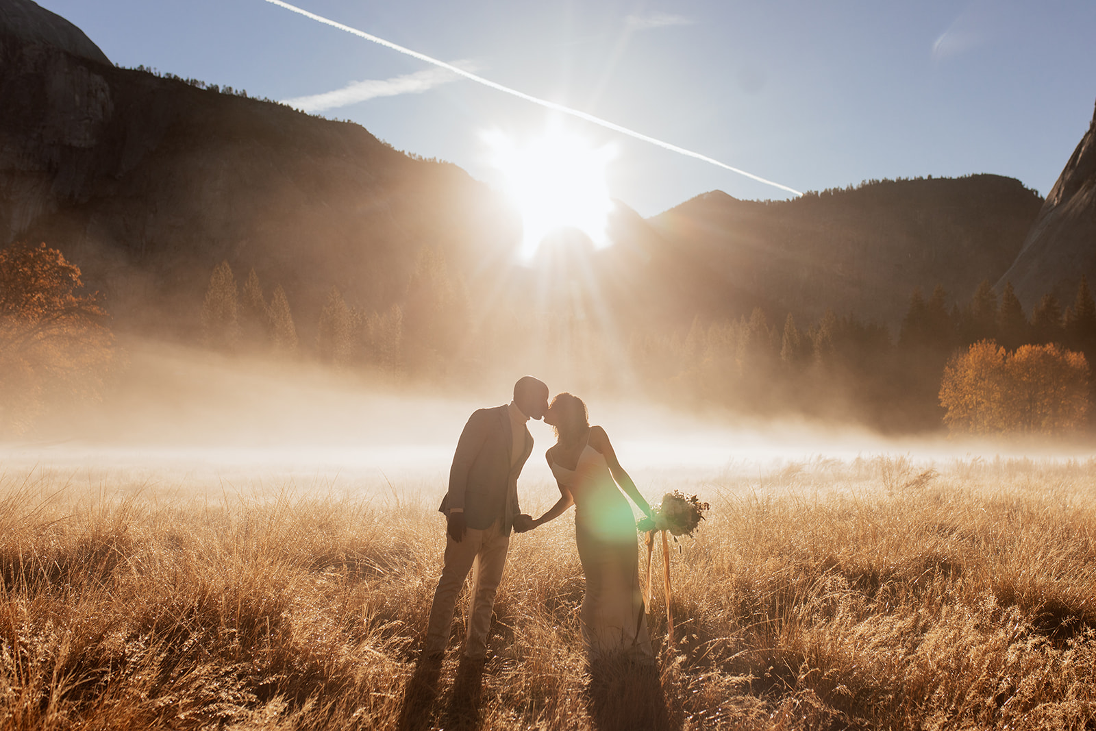 couple kisses in field at sunrise Yosemite elopement