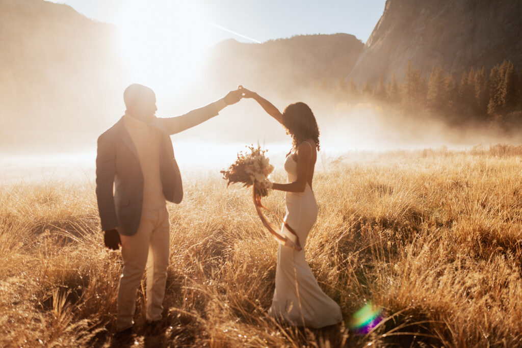 couple twirls through sunny foggy field 
