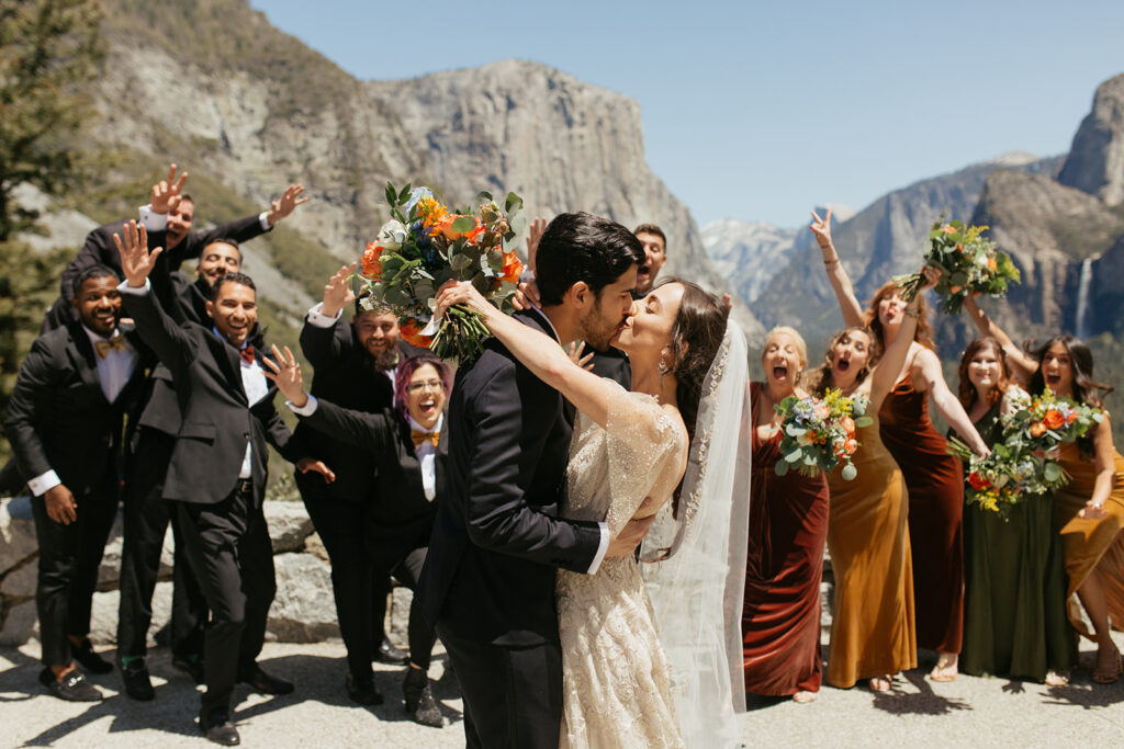 couple kisses with wedding party at Yosemite Tunnel View