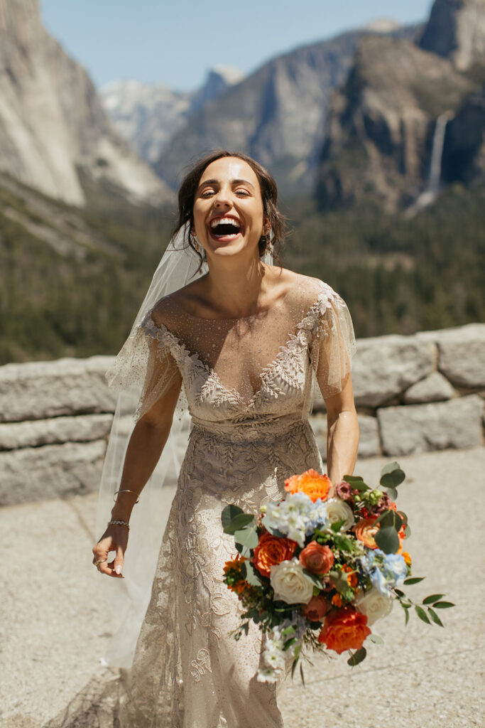 bride laughs while holding colorful wedding bouquet