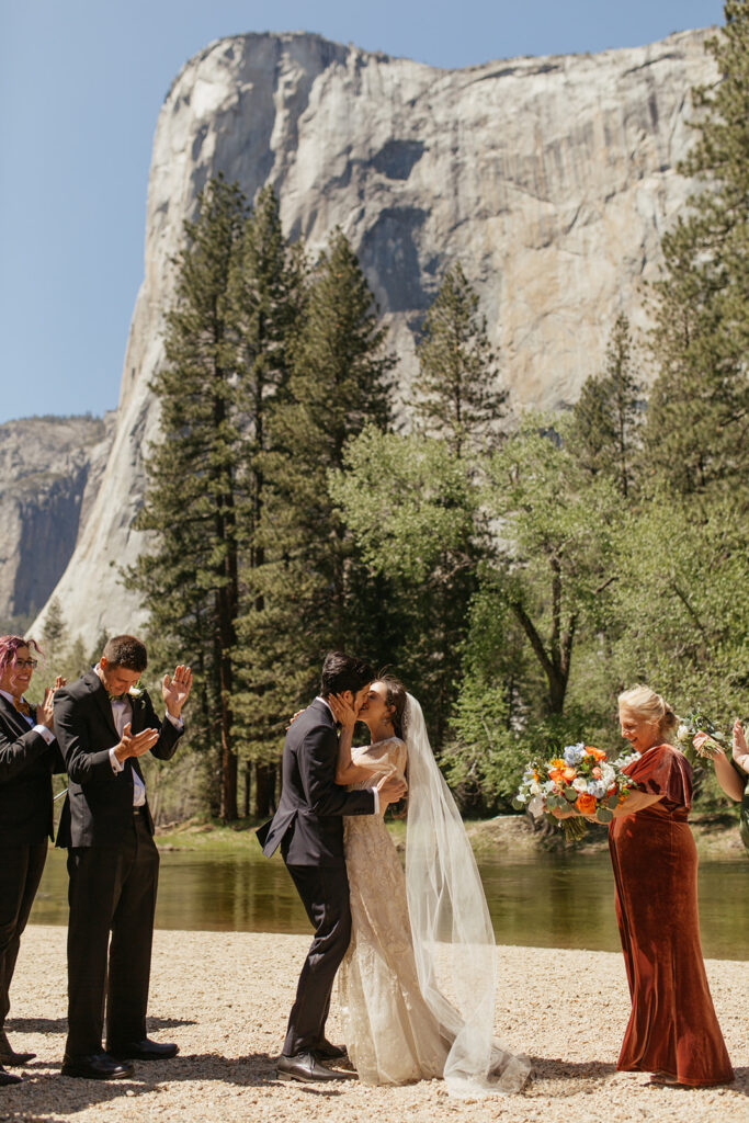 couple kisses during Merced River wedding ceremony