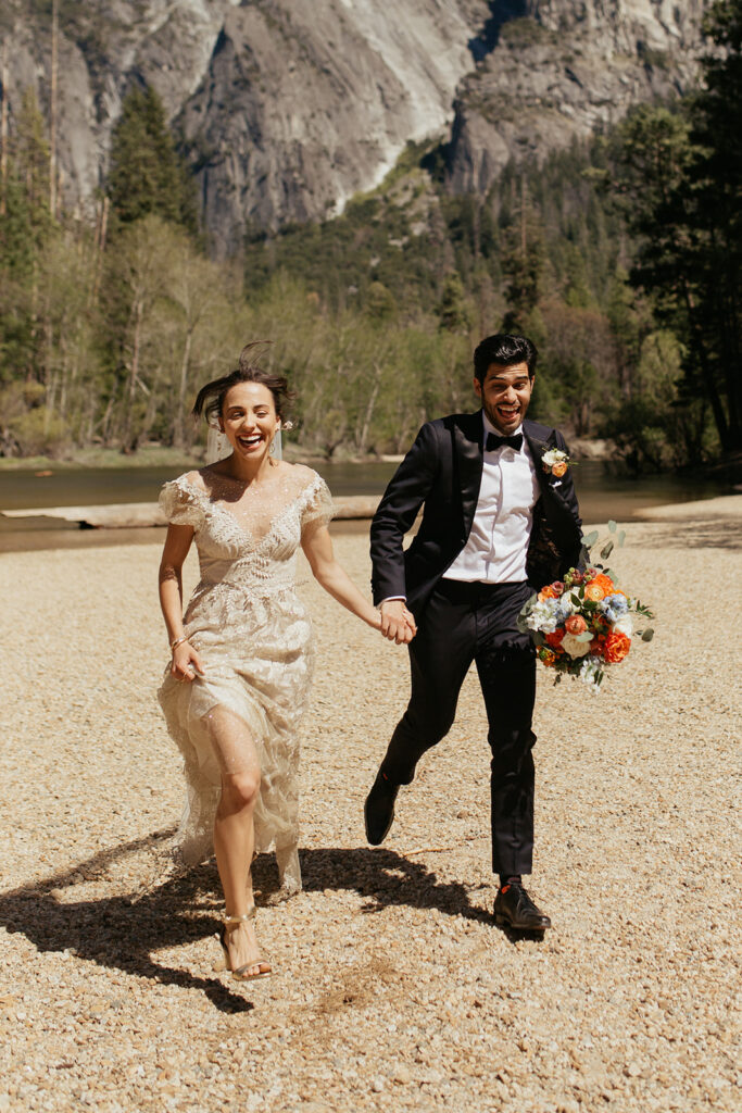 couple runs together beside Merced River elopement