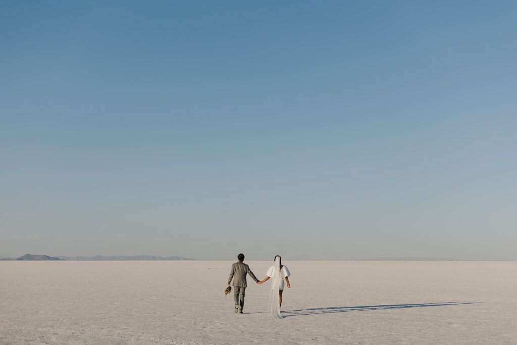 couple walks holding hands at Bonneville Salt Flats sunset elopement