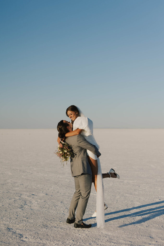 groom lifts bride at Bonneville Salt Flats sunset elopement
