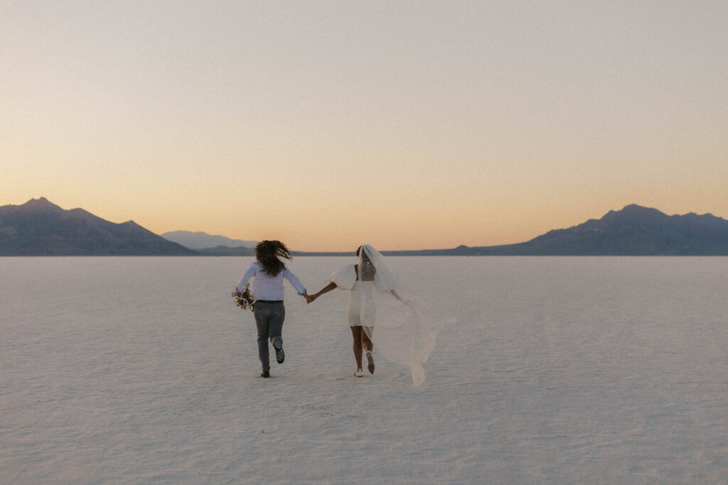 couple runs holding hands at Bonneville Salt Flats sunset elopement