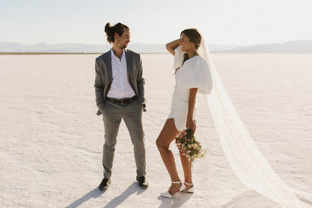 couple smiles at each other during salt flats sunset elopement