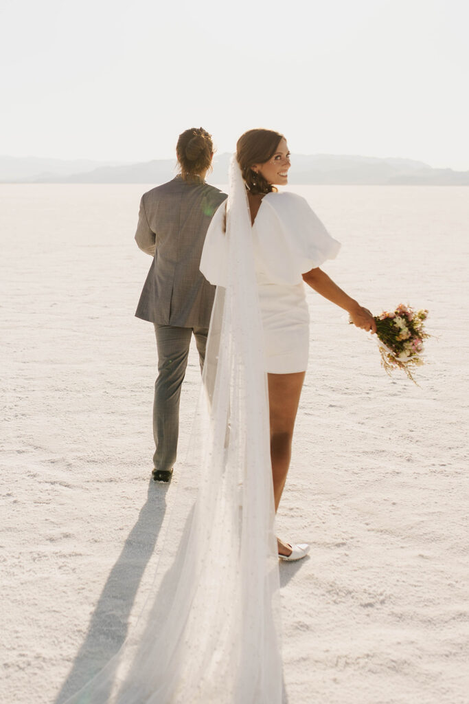 couple walks holding hands at Bonneville Salt Flats sunset elopement